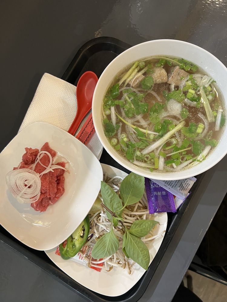 Bowl of phở with a side plate of rare beef and onion